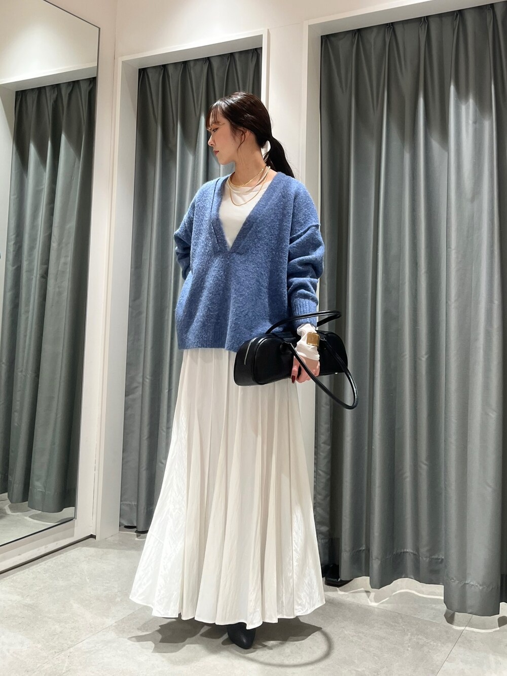 ホワイト系のスカート、ブラック系のショルダーバッグ、ブルー系のニット/セーターを着用したレディースの冬コーディネートの4枚目の写真