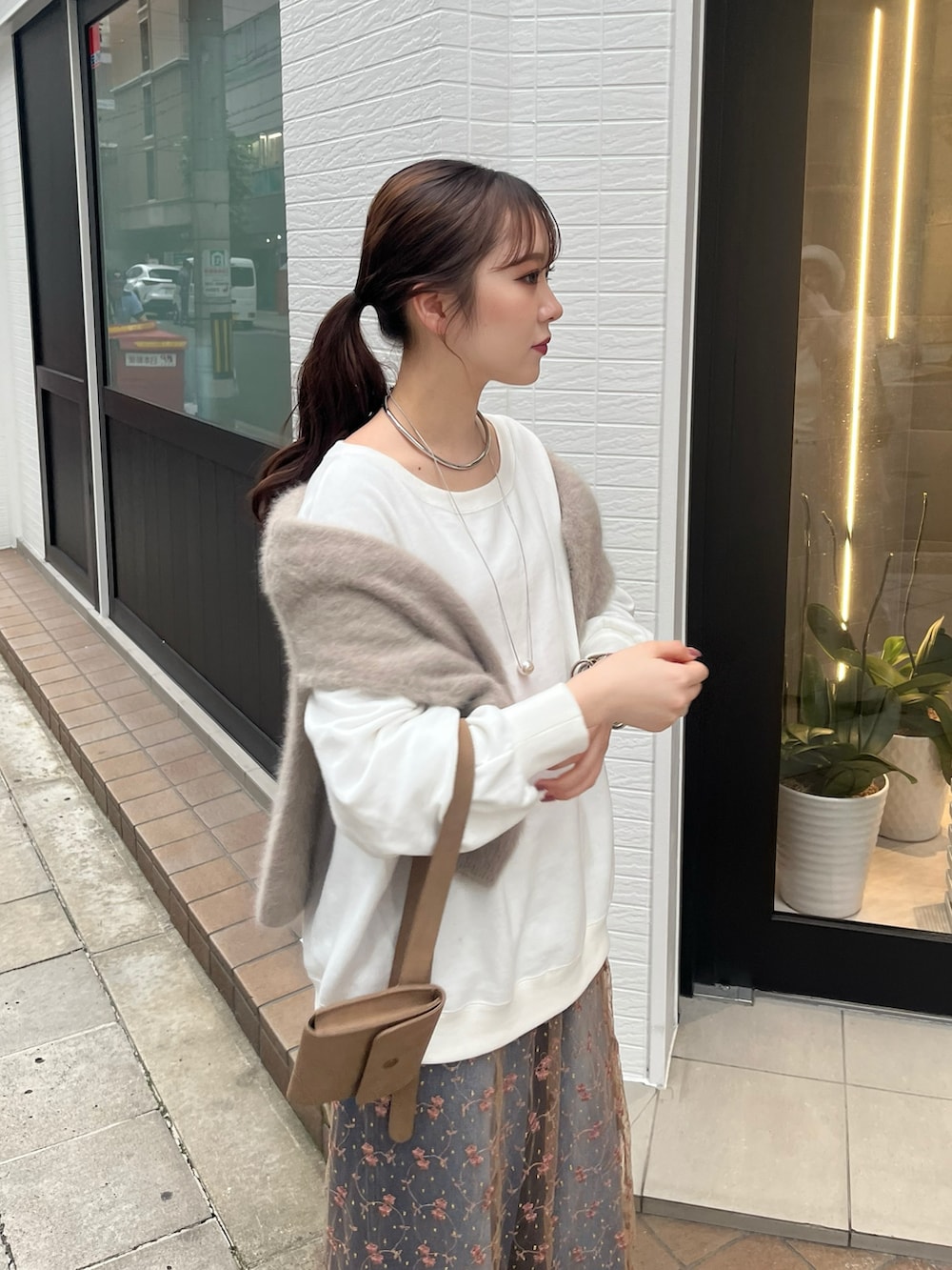 ピンク系のスカート、ブルー系のデニムパンツ、ベージュ系のショルダーバッグを着用したレディースの秋コーディネートの2枚目の写真