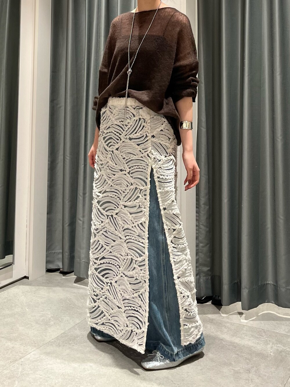 ブルー系のデニムパンツ、シルバー系のバレエシューズ、ホワイト系のスカートを着用したレディースの夏コーディネートの6枚目の写真