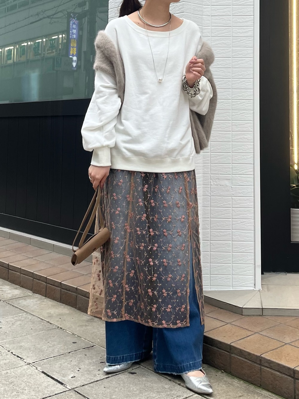 ピンク系のスカート、ブルー系のデニムパンツ、ベージュ系のショルダーバッグを着用したレディースの秋コーディネートの6枚目の写真