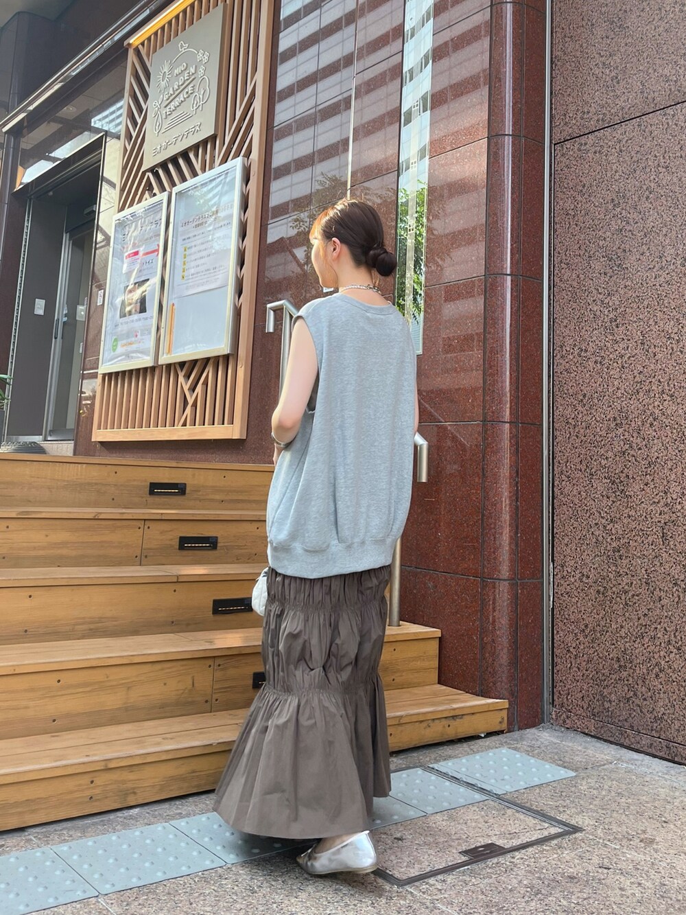 ブラウン系のスカート、シルバー系のブーツ、ホワイト系のショルダーバッグを着用したレディースの夏コーディネートの2枚目の写真