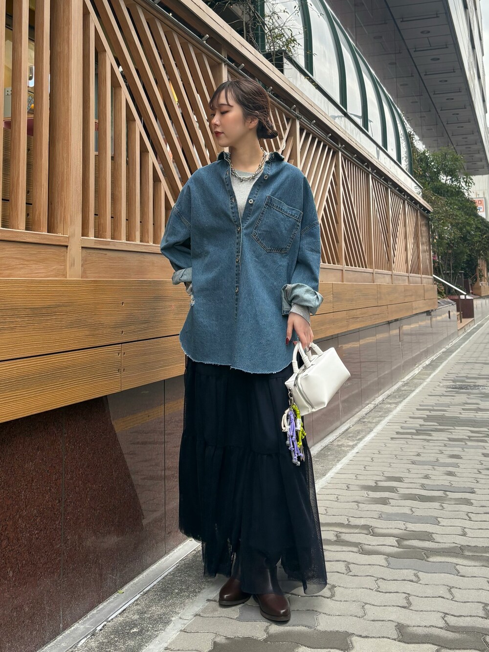 ブルー系のスカート、ブラウン系のブーツ、ホワイト系のショルダーバッグを着用したレディースの冬コーディネートの3枚目の写真