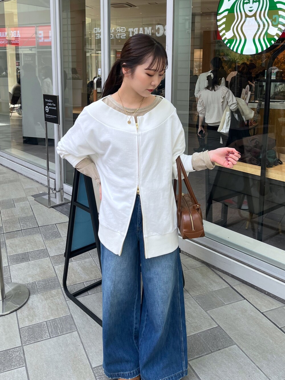 ブルー系のデニムパンツ、ベージュ系のその他アウター、ホワイト系のTシャツ/カットソーを着用したレディースの冬コーディネートの3枚目の写真