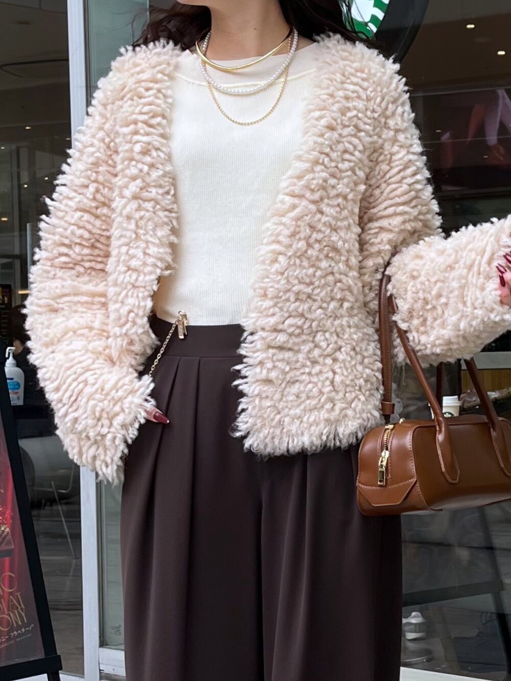 ブラウン系のスラックス、ブラウン系のショルダーバッグ、ベージュ系のカーディガン/ボレロを着用したレディースの冬コーディネートの6枚目の写真