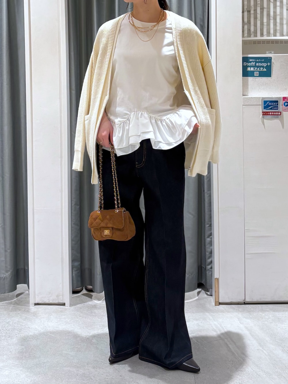 ブルー系のデニムパンツ、ブラウン系のパンプス、ホワイト系のTシャツ/カットソーを着用したレディースの冬コーディネートの2枚目の写真