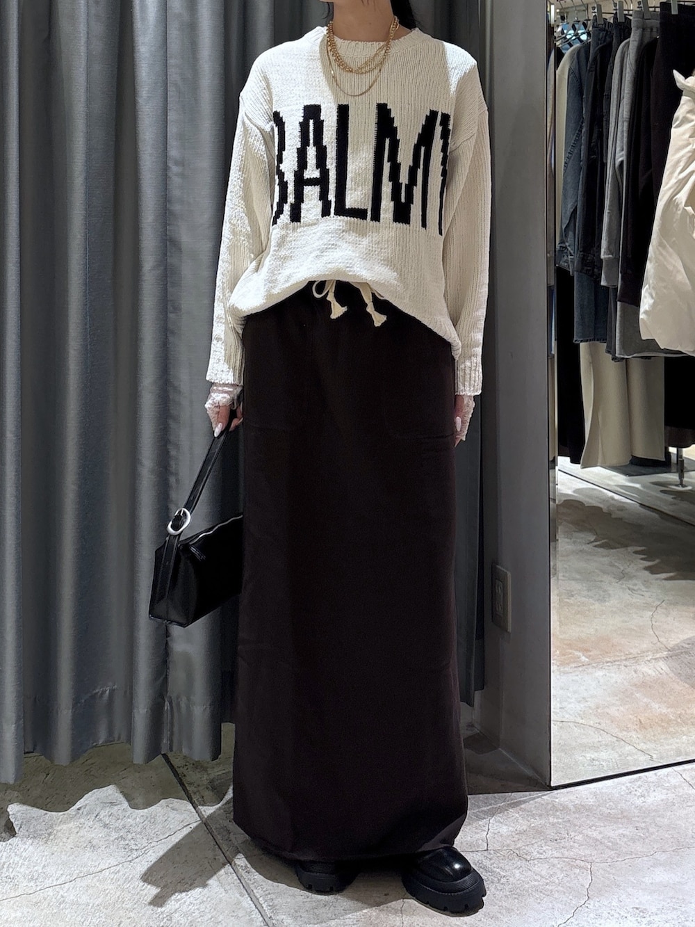 ホワイト系のニット/セーター、ブラウン系のスカート、ブラック系のブーツを着用したレディースの冬コーディネートの3枚目の写真