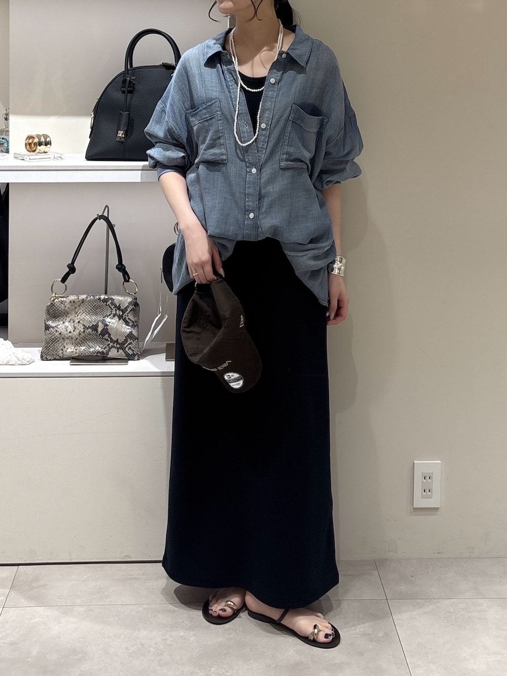 ブラック系のワンピース、ブルー系のシャツ/ブラウス、ホワイト系のネックレスを着用したレディースの夏コーディネートの2枚目の写真