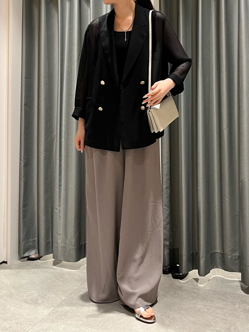 グレー系のその他パンツ、ホワイト系のショルダーバッグ、ブラック系のテーラードジャケットを着用したレディースの夏コーディネートの3枚目の写真