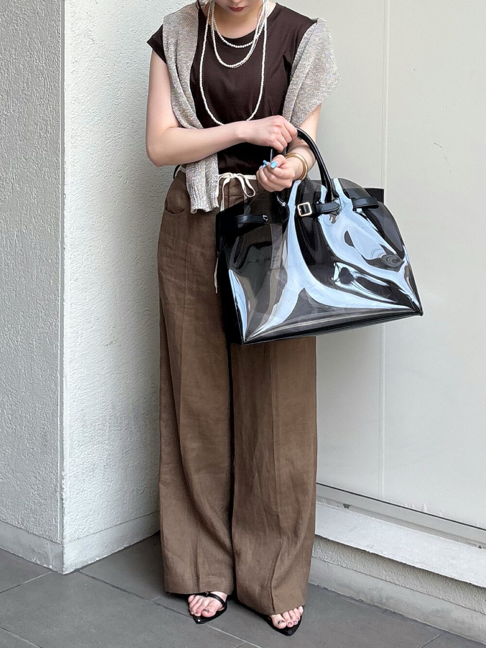 ブラック系のサンダル、ブラック系のショルダーバッグ、ゴールド系のニット/セーターを着用したレディースの夏コーディネートの4枚目の写真