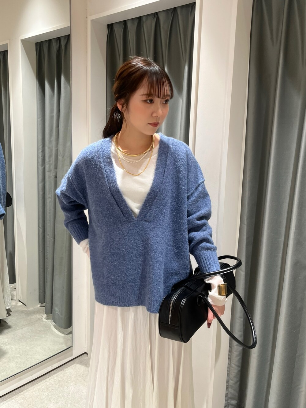 ホワイト系のスカート、ブラック系のショルダーバッグ、ブルー系のニット/セーターを着用したレディースの冬コーディネートの2枚目の写真