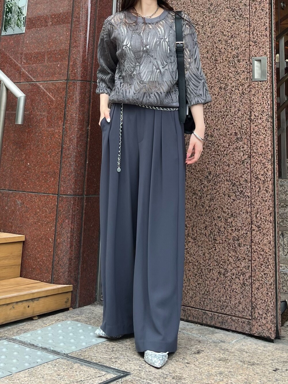 グレー系のスラックス、シルバー系のパンプス、ブラック系のショルダーバッグを着用したレディースの秋コーディネートの4枚目の写真