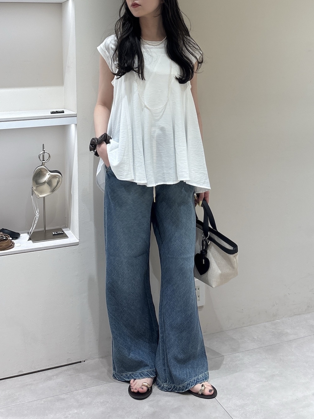 ホワイト系のキャミソール、ホワイト系のTシャツ/カットソー、ブルー系のデニムパンツを着用したレディースの春コーディネートの2枚目の写真