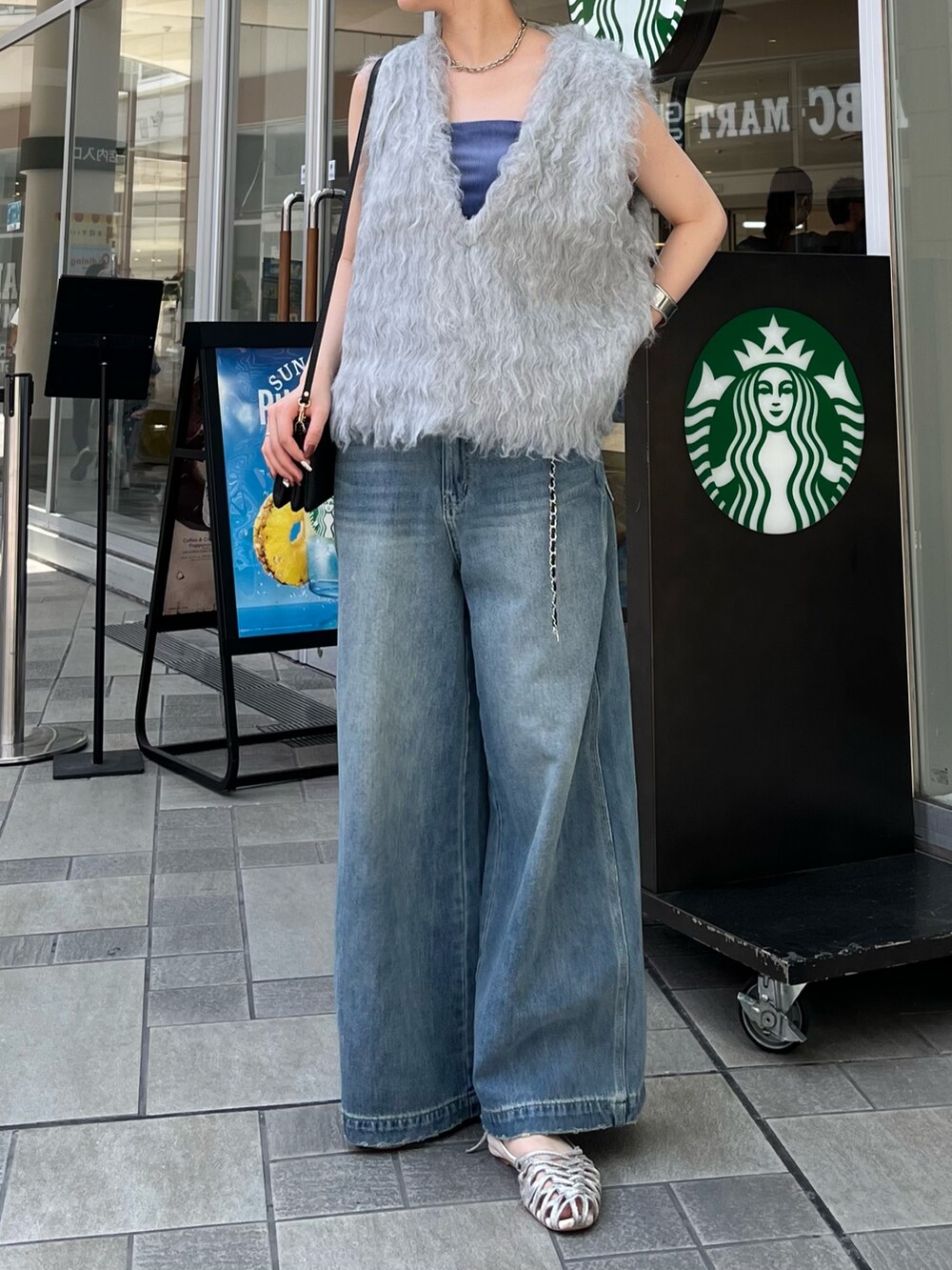 ブルー系のデニムパンツ、シルバー系のパンプス、ブルー系のキャミソールを着用したレディースの夏コーディネートの6枚目の写真