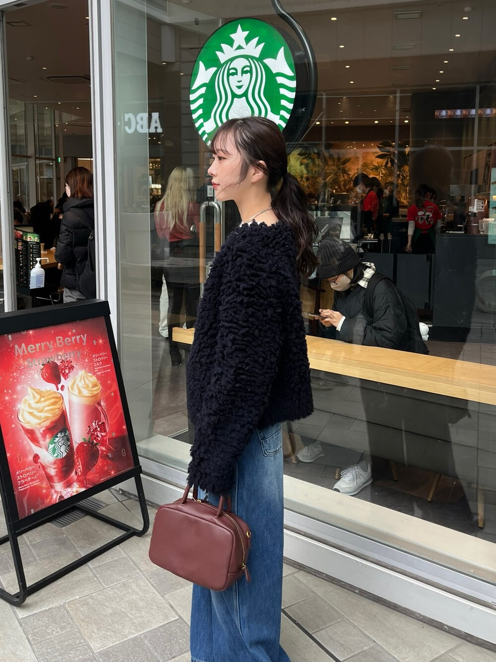 ブルー系のデニムパンツ、ブラウン系のショルダーバッグ、ブルー系のカーディガン/ボレロを着用したレディースの冬コーディネートの4枚目の写真