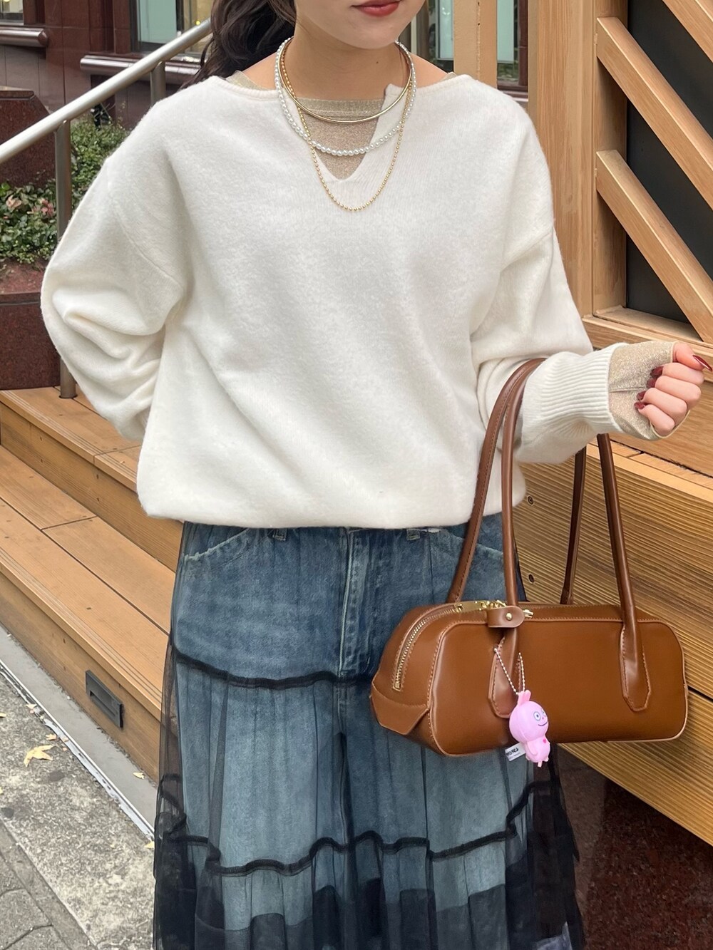 ブルー系のデニムパンツ、ブラック系のスカート、ホワイト系のニット/セーターを着用したレディースの冬コーディネートの8枚目の写真