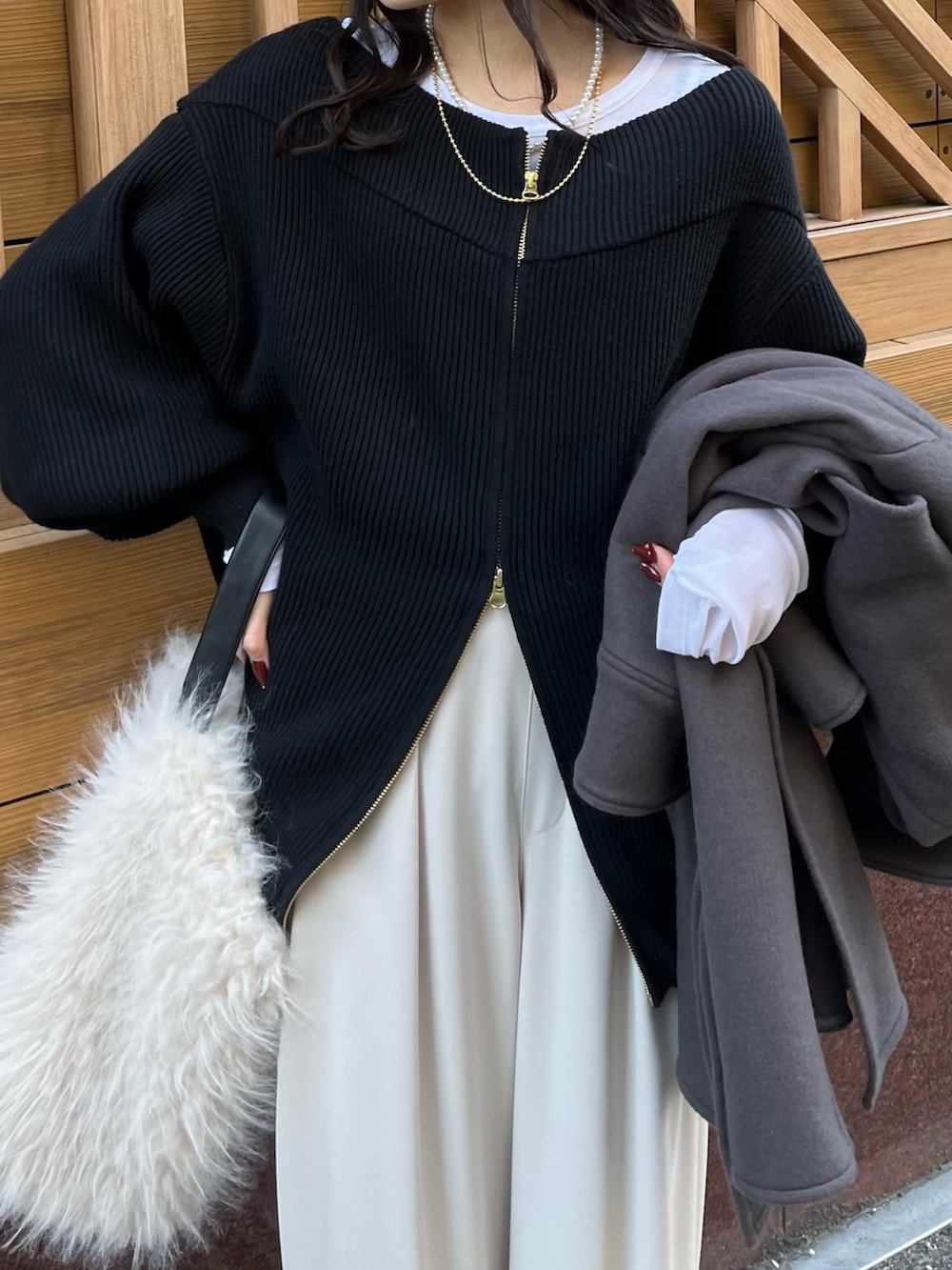グレー系のスラックス、ブラック系のニット/セーター、ホワイト系のTシャツ/カットソーを着用したレディースの冬コーディネートの5枚目の写真