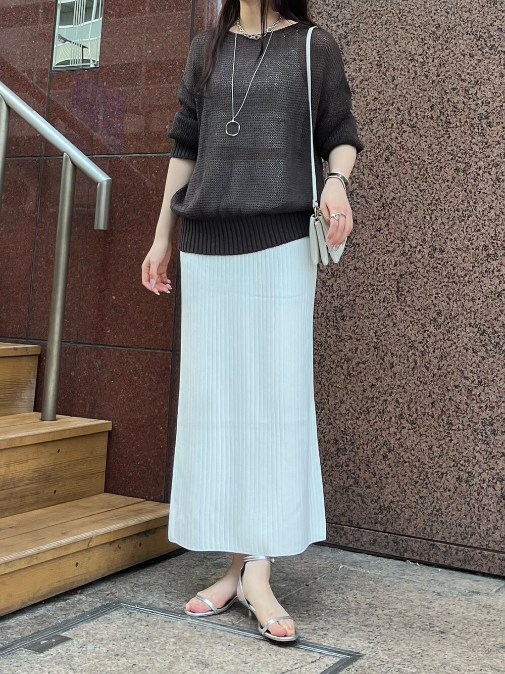 ブラウン系のニット/セーター、ホワイト系のスカート、シルバー系のサンダルを着用したレディースの夏コーディネートの3枚目の写真