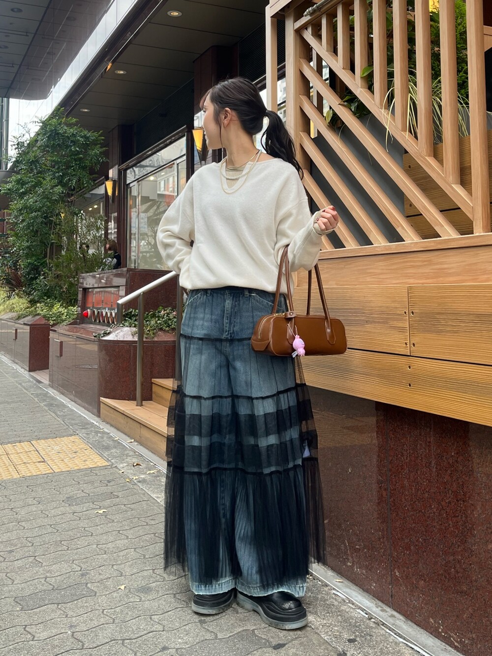 ブルー系のデニムパンツ、ブラック系のスカート、ホワイト系のニット/セーターを着用したレディースの冬コーディネートの5枚目の写真