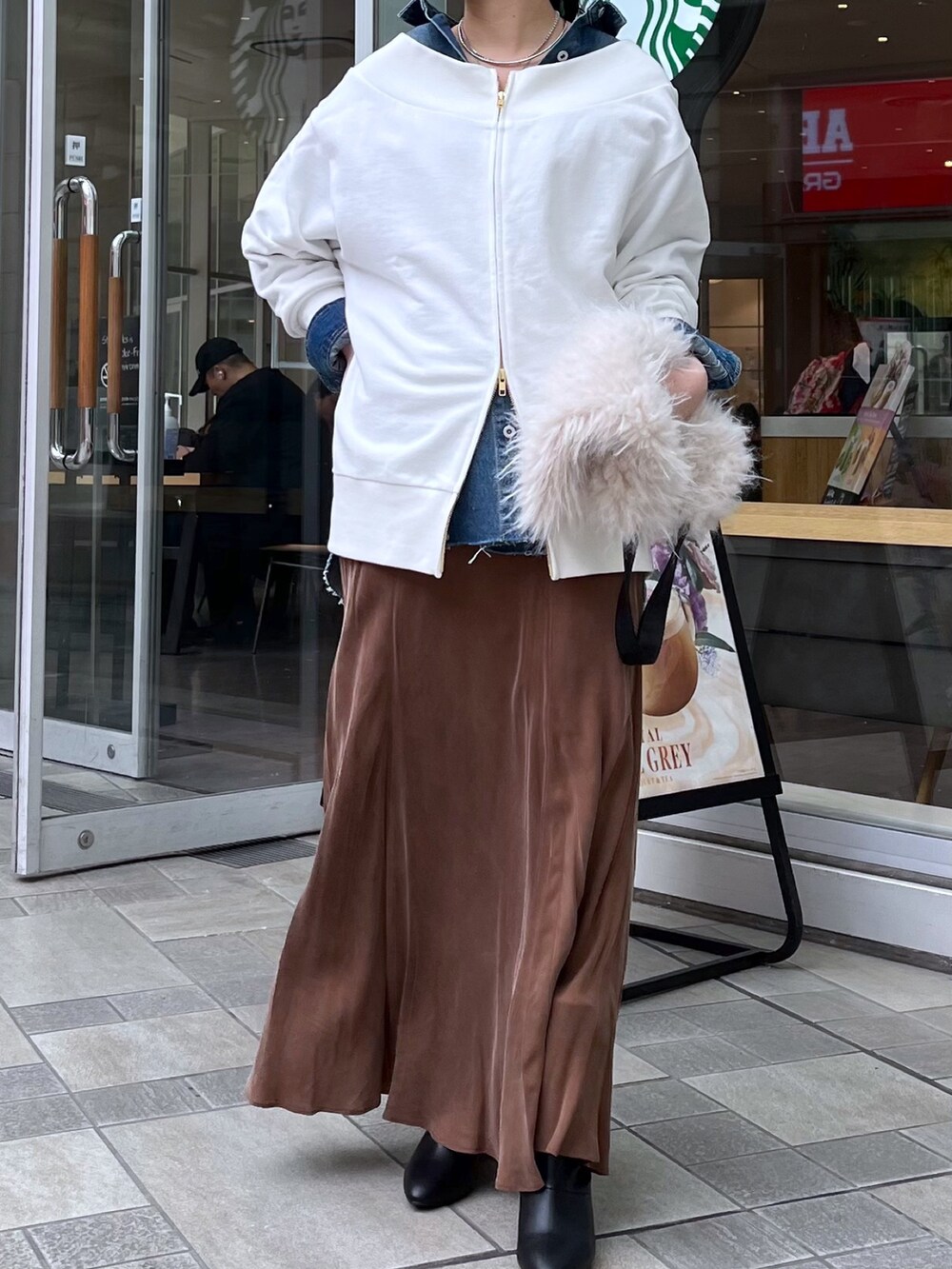 ブラウン系のスカート、ブラック系のブーツ、ホワイト系のTシャツ/カットソーを着用したレディースの冬コーディネートの4枚目の写真