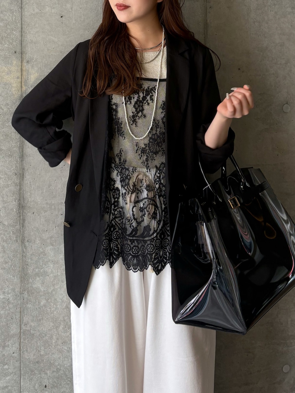 ブラック系のシャツ/ブラウス、ベージュ系のニット/セーター、ブラック系のテーラードジャケットを着用したレディースの春コーディネートの2枚目の写真