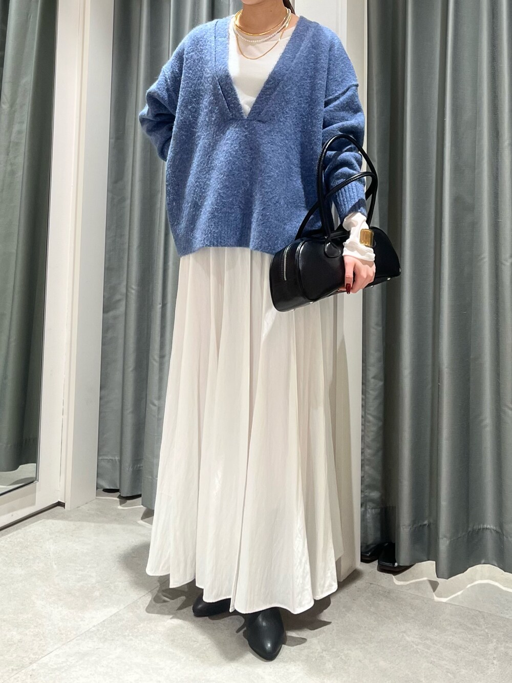 ホワイト系のスカート、ブラック系のショルダーバッグ、ブルー系のニット/セーターを着用したレディースの冬コーディネートの5枚目の写真