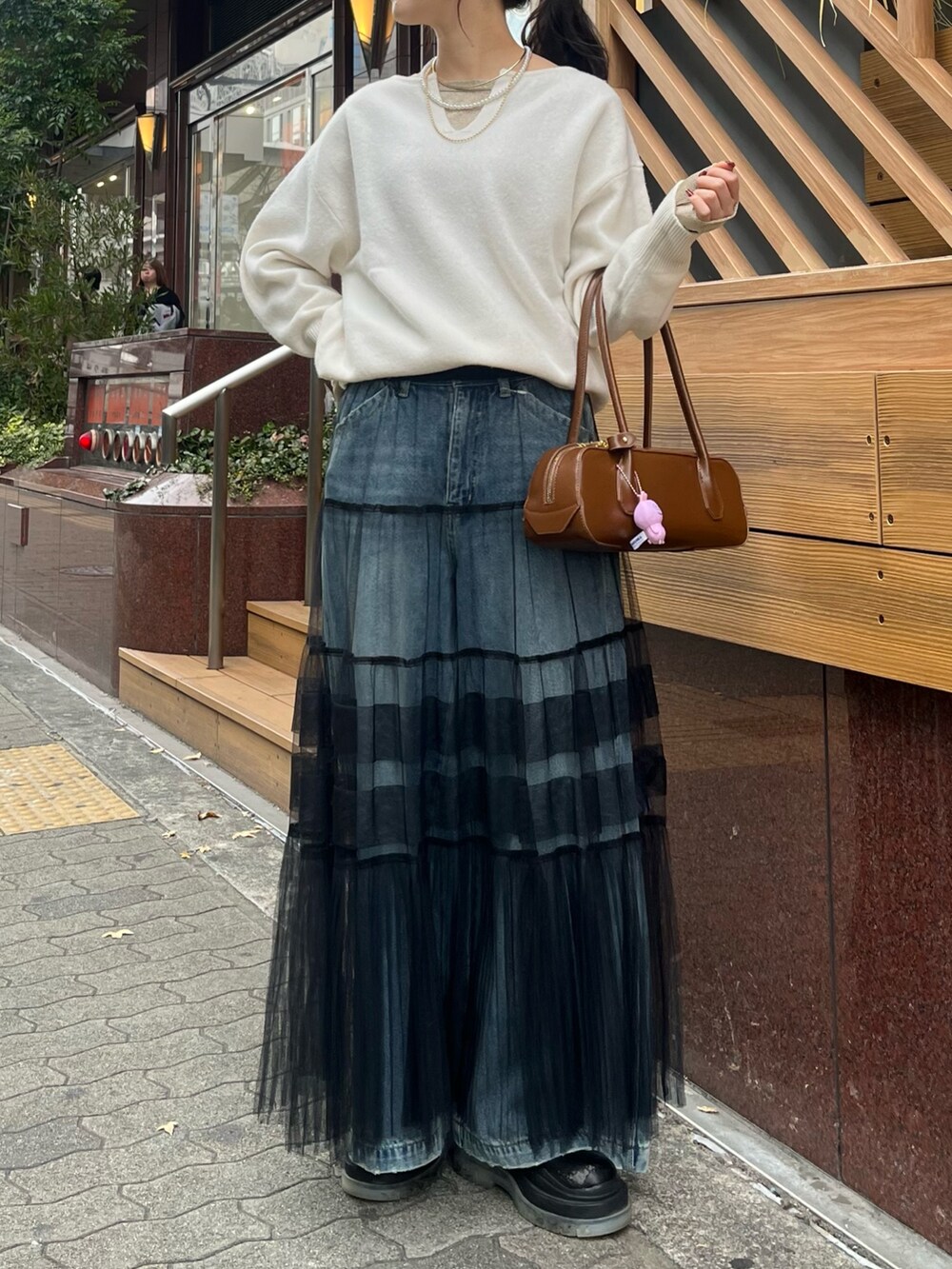 ブルー系のデニムパンツ、ブラック系のスカート、ホワイト系のニット/セーターを着用したレディースの冬コーディネートの4枚目の写真