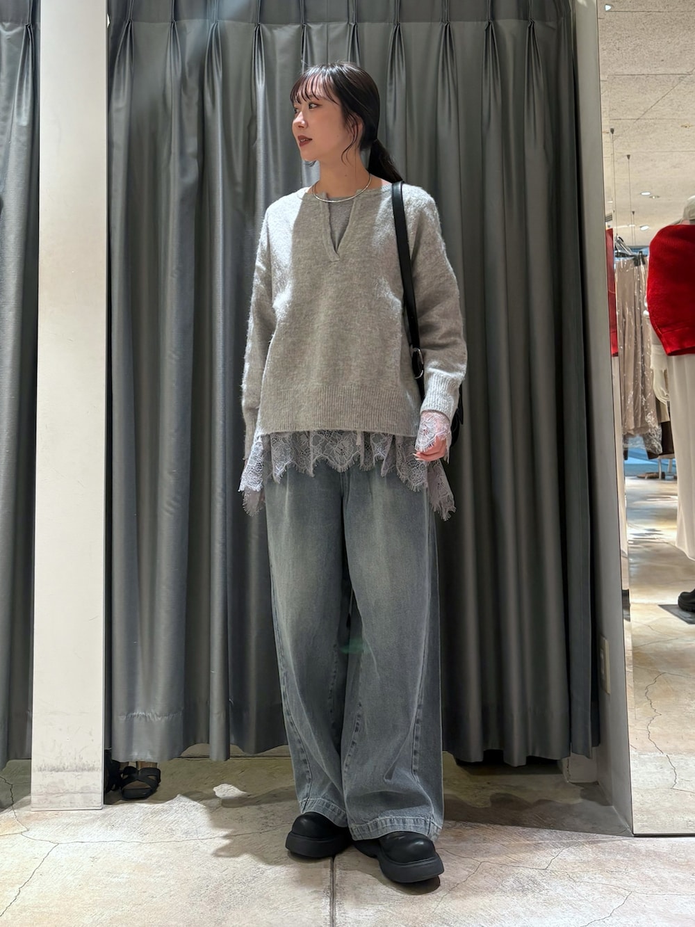 グレー系のニット/セーター、グレー系のTシャツ/カットソー、ブルー系のデニムパンツを着用したレディースの冬コーディネートの2枚目の写真