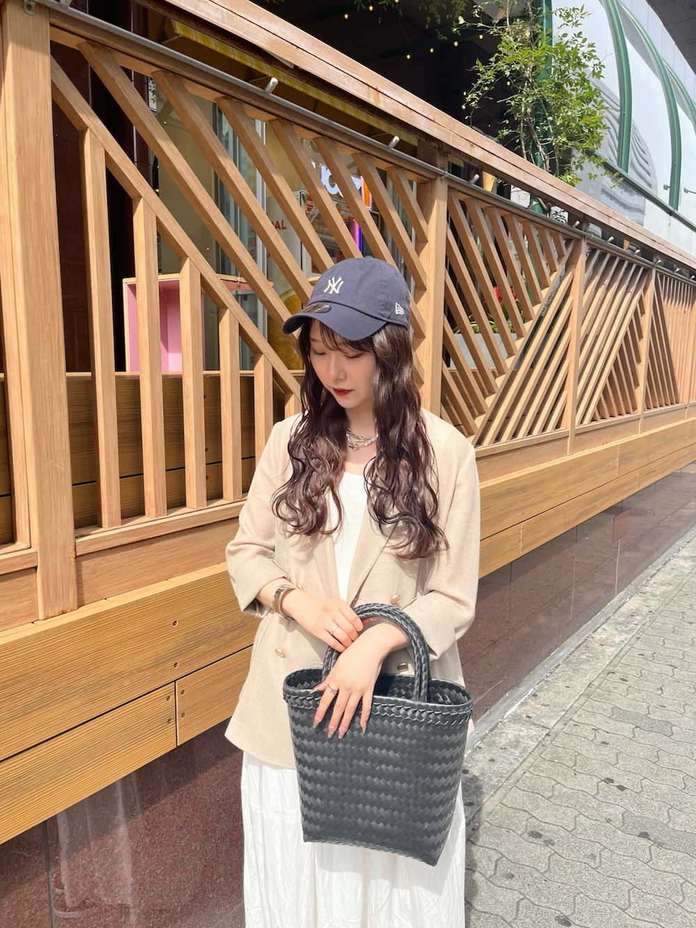 ベージュ系のテーラードジャケット、ホワイト系のワンピース、ブラック系のかごバッグを着用したレディースの夏コーディネートの4枚目の写真