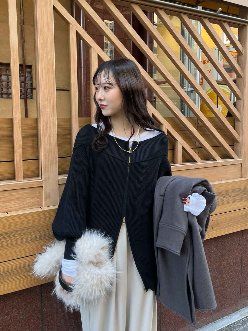 グレー系のスラックス、ブラック系のニット/セーター、ホワイト系のTシャツ/カットソーを着用したレディースの冬コーディネートの2枚目の写真