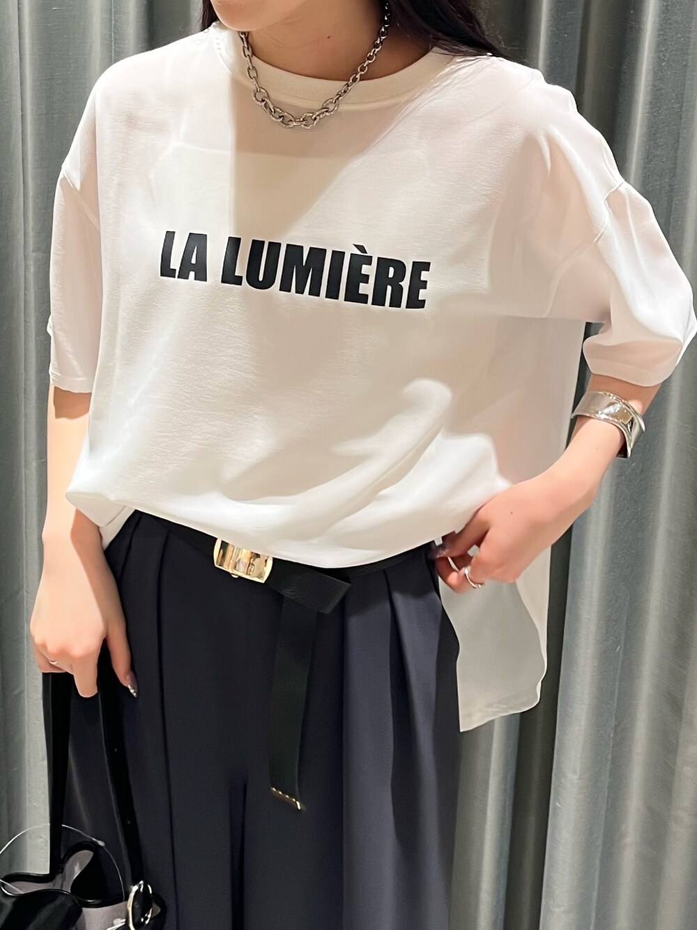 グレー系のスラックス、ブラック系のバッグ、シルバー系のパンプスを着用したレディースの夏コーディネートの7枚目の写真