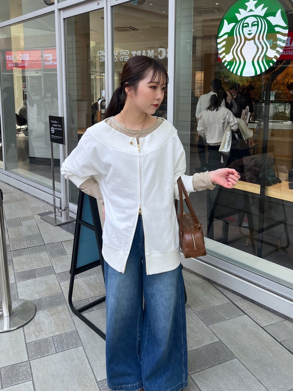 ブルー系のデニムパンツ、ベージュ系のその他アウター、ホワイト系のTシャツ/カットソーを着用したレディースの冬コーディネートの6枚目の写真