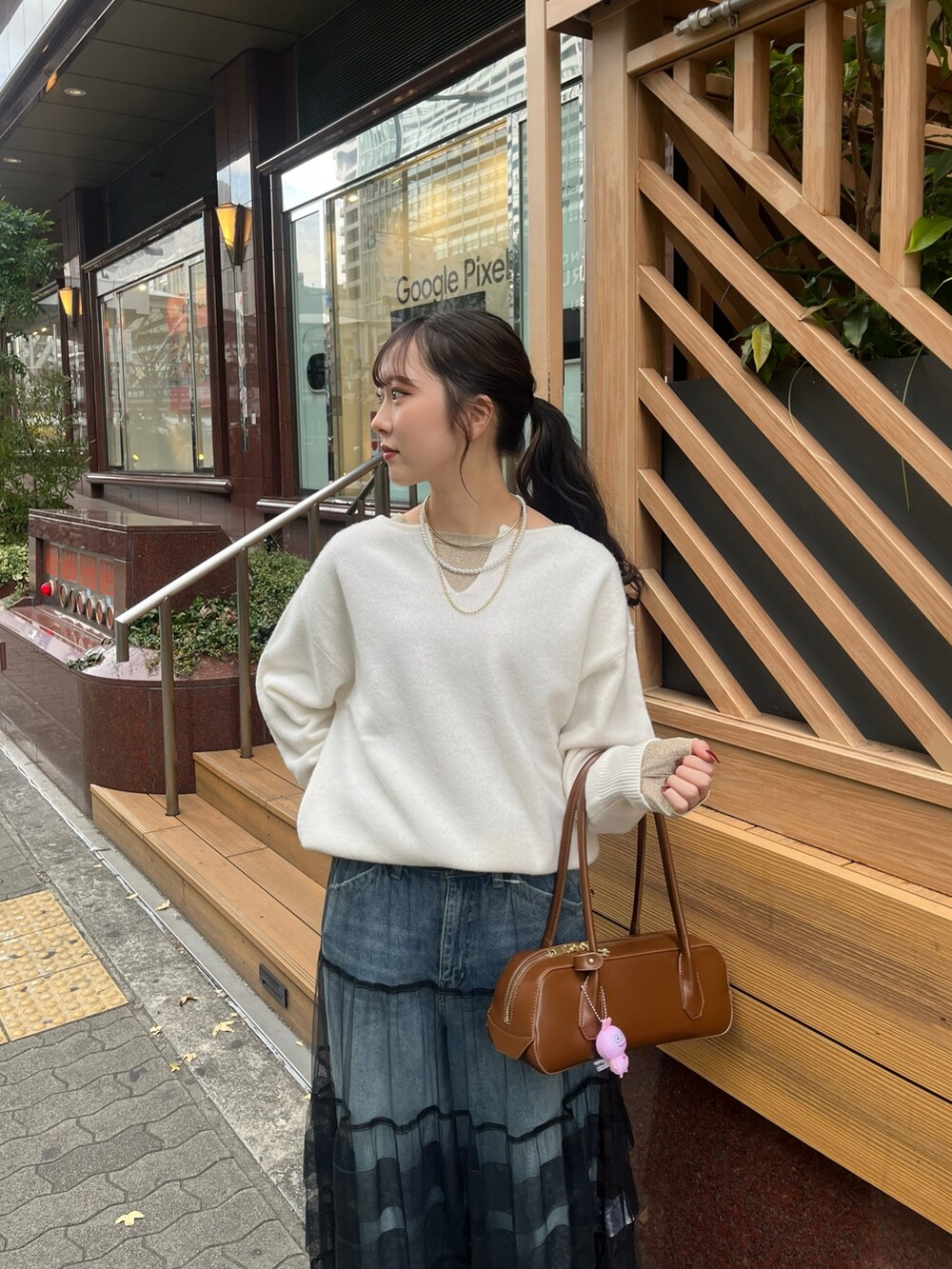 ブルー系のデニムパンツ、ブラック系のスカート、ホワイト系のニット/セーターを着用したレディースの冬コーディネートの3枚目の写真