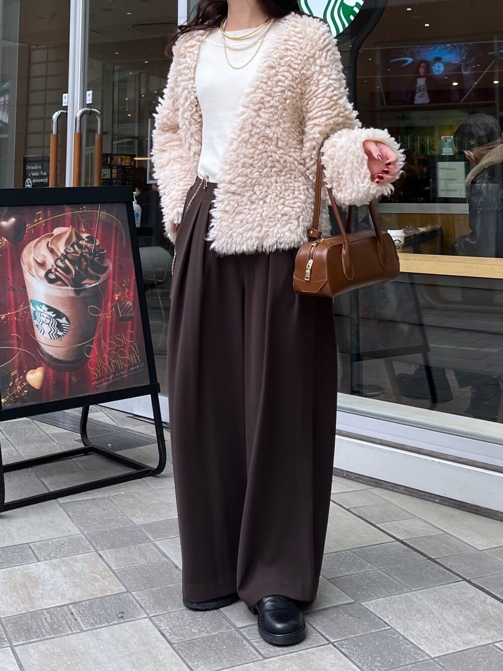 ブラウン系のスラックス、ブラウン系のショルダーバッグ、ベージュ系のカーディガン/ボレロを着用したレディースの冬コーディネートの5枚目の写真