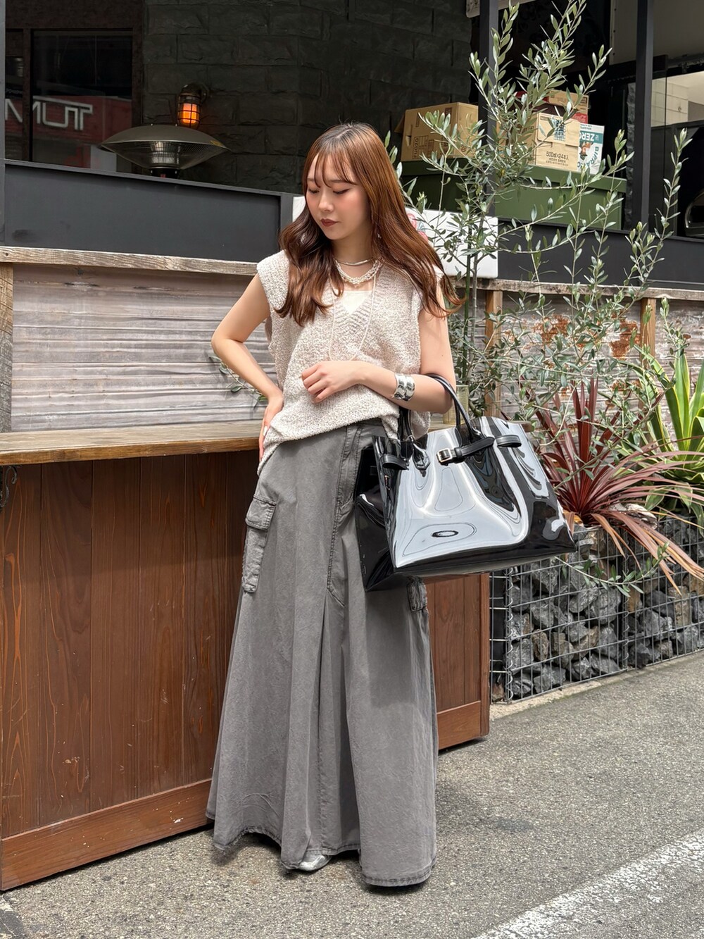 ブラック系のスカート、ブラック系のショルダーバッグ、ベージュ系のニット/セーターを着用したレディースの春コーディネートの2枚目の写真