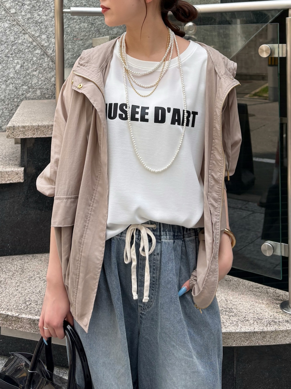 ブルー系のデニムパンツ、ブラック系のショルダーバッグ、ベージュ系のその他アウターを着用したレディースの夏コーディネートの6枚目の写真