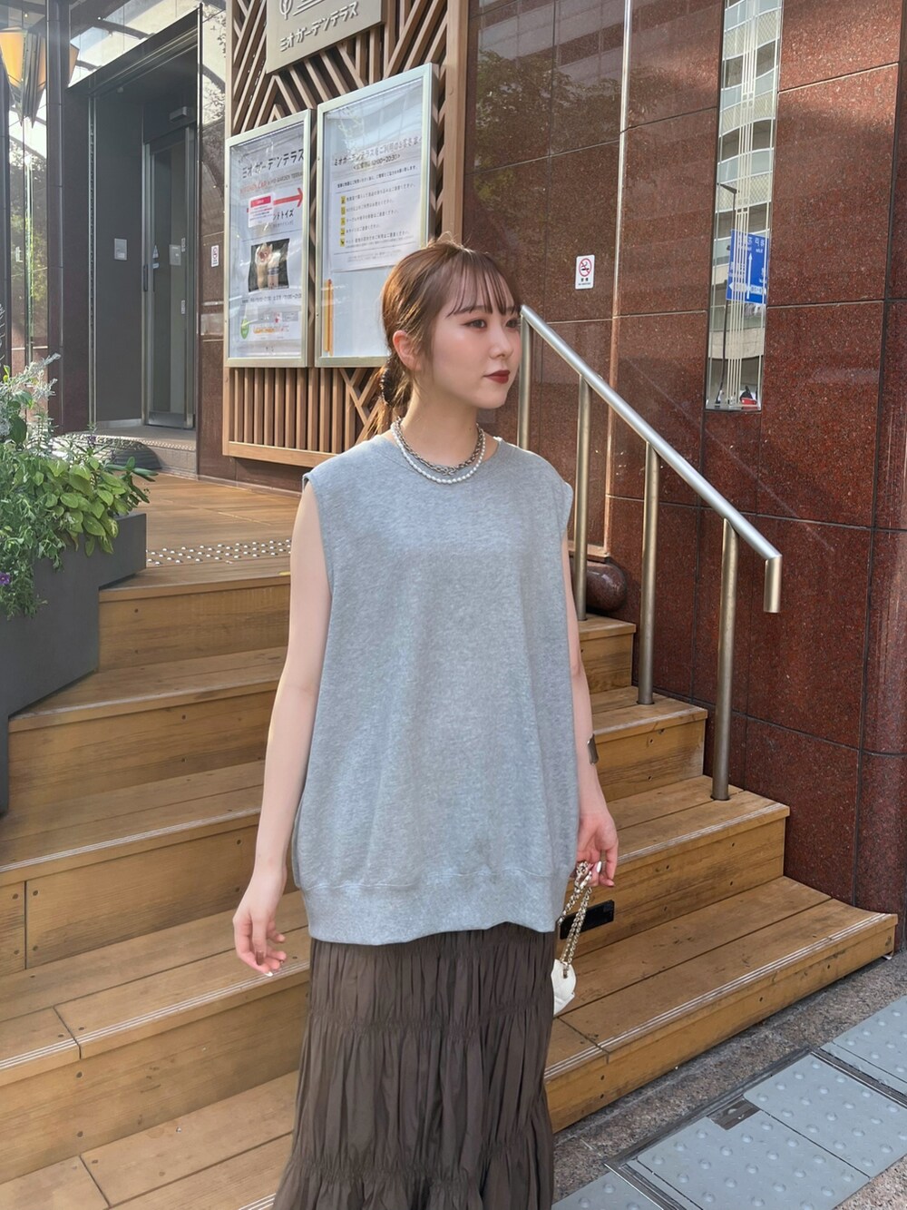 ブラウン系のスカート、シルバー系のブーツ、ホワイト系のショルダーバッグを着用したレディースの夏コーディネートの3枚目の写真