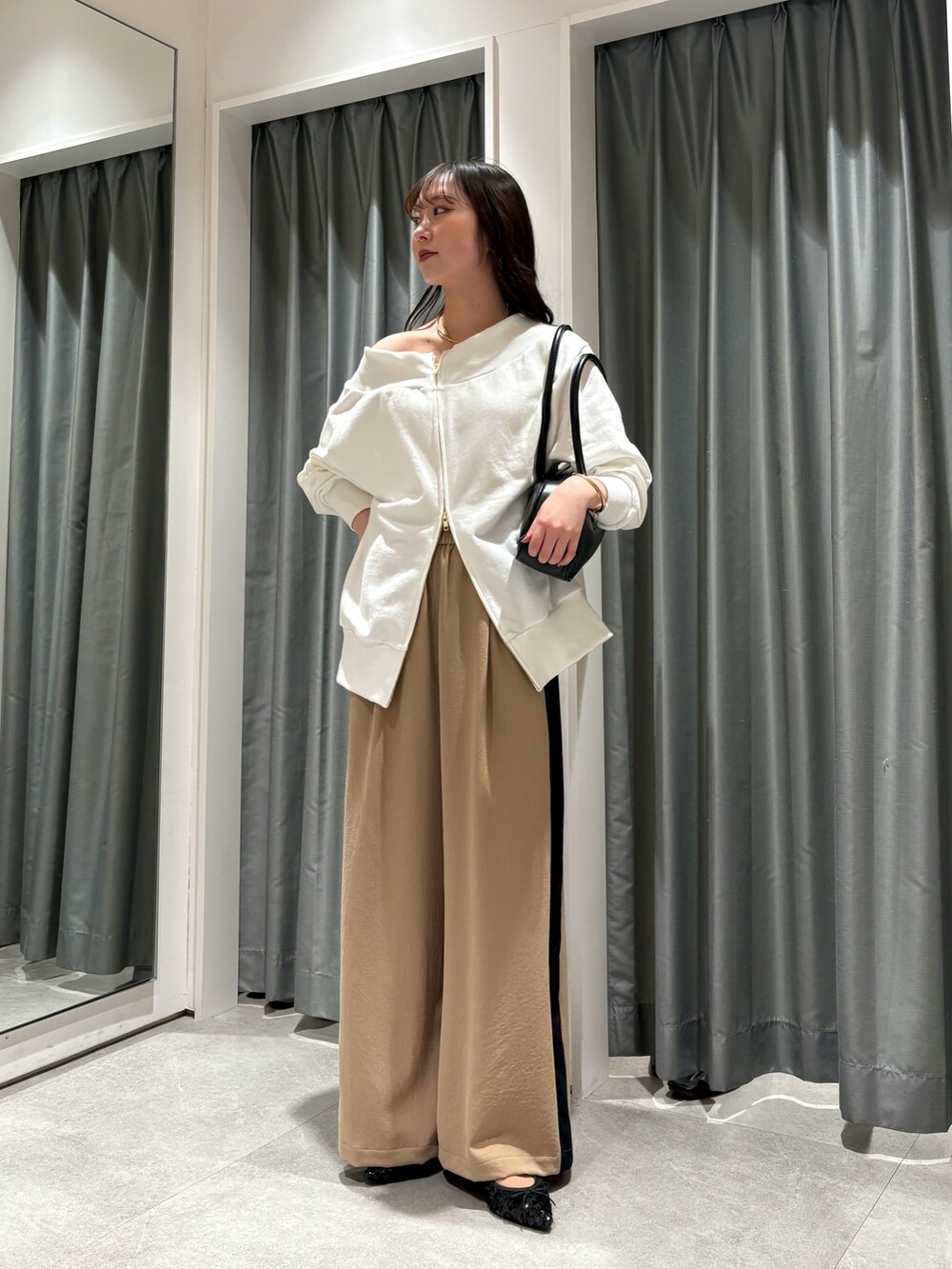 ベージュ系のその他パンツ、ホワイト系のTシャツ/カットソー、ブラック系のショルダーバッグを着用したレディースの冬コーディネートの3枚目の写真