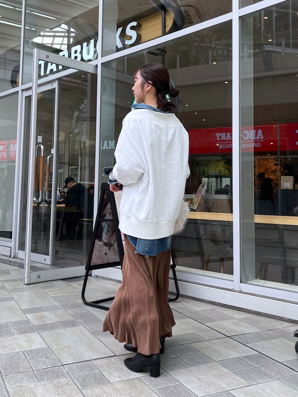 ブラウン系のスカート、ブラック系のブーツ、ホワイト系のTシャツ/カットソーを着用したレディースの冬コーディネートの2枚目の写真