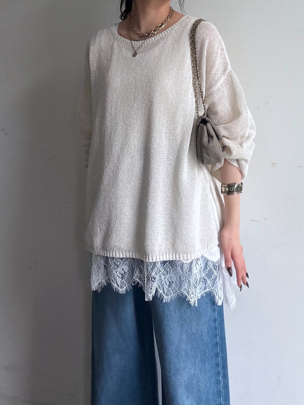 ホワイト系のニット/セーター、ブルー系のデニムパンツ、ホワイト系のTシャツ/カットソーを着用したレディースの春コーディネートの3枚目の写真