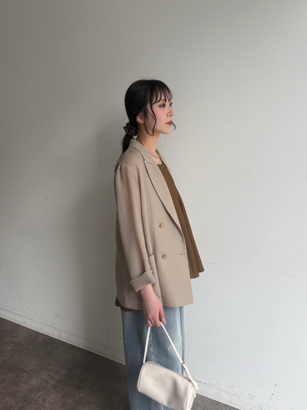 ベージュ系のテーラードジャケット、ブルー系のデニムパンツを着用したレディースの春コーディネートの2枚目の写真