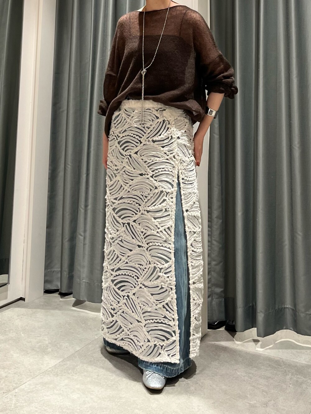 ブルー系のデニムパンツ、シルバー系のバレエシューズ、ホワイト系のスカートを着用したレディースの夏コーディネートの7枚目の写真