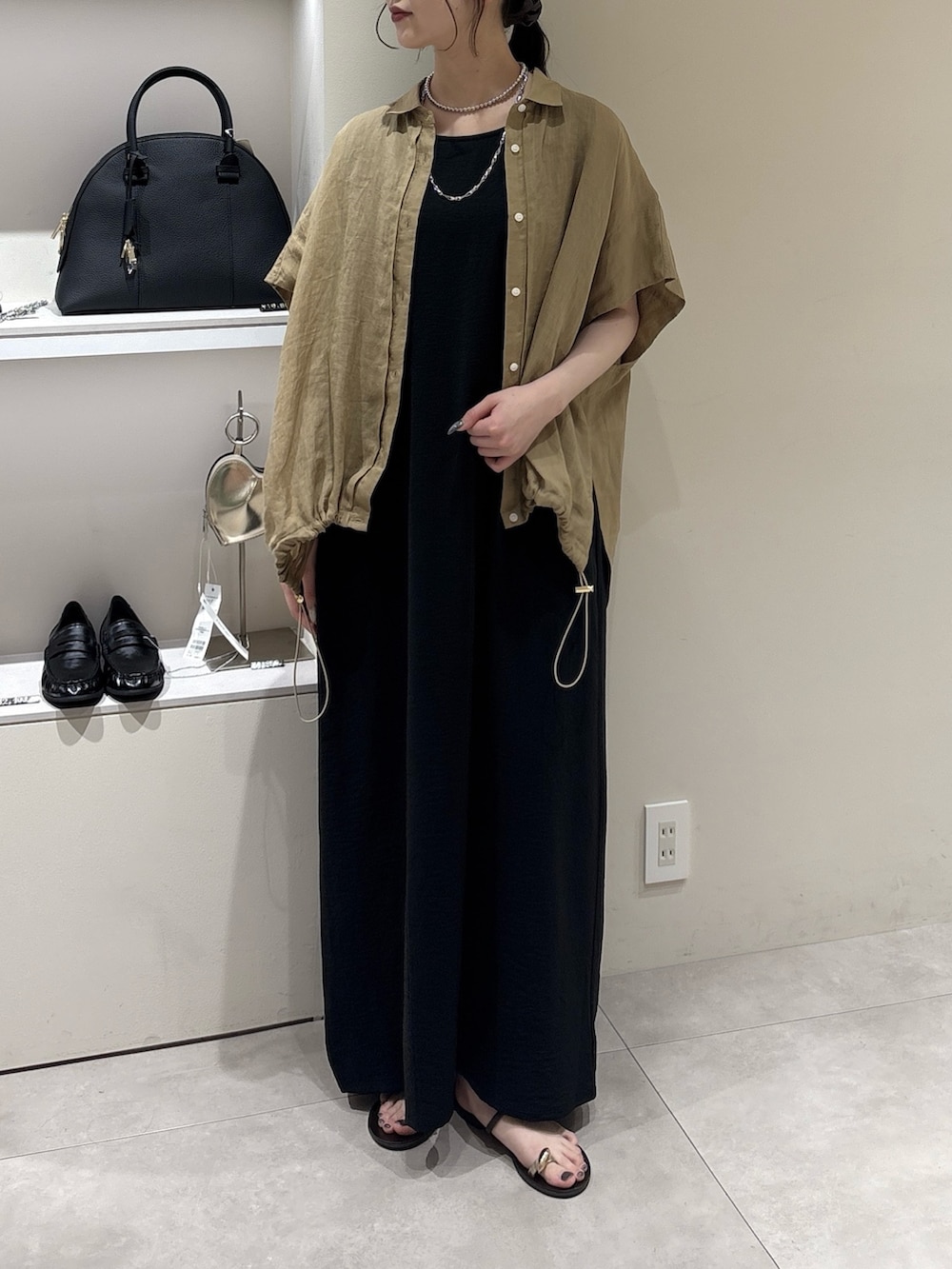 ブラック系のワンピース、ベージュ系のシャツ/ブラウス、シルバー系のネックレスを着用したレディースの夏コーディネートの2枚目の写真