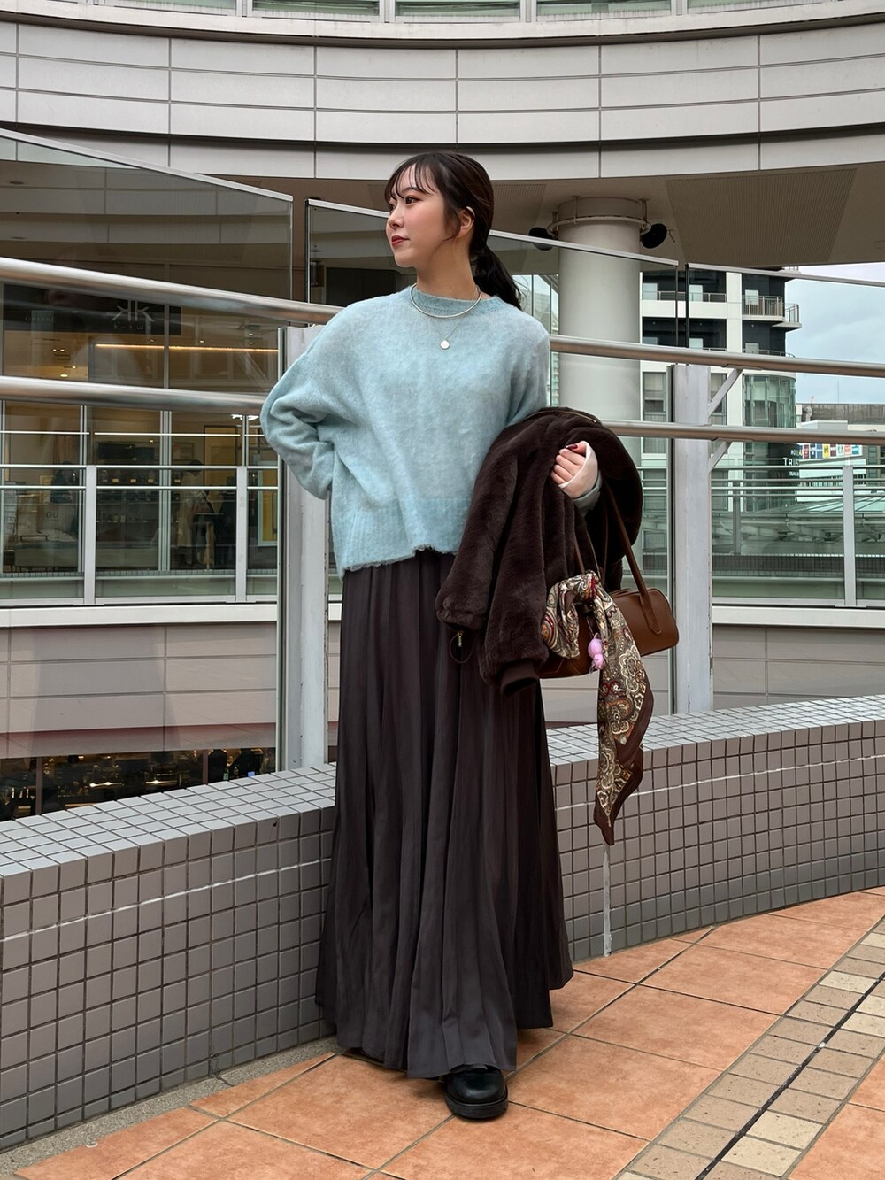 グレー系のスカート、ブラウン系のショルダーバッグ、ブラウン系のその他アウターを着用したレディースの冬コーディネートの6枚目の写真