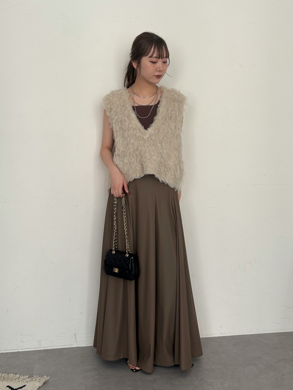 ブラウン系のタンクトップ、ブラック系のショルダーバッグ、ベージュ系のニット/セーターを着用したレディースの夏コーディネートの2枚目の写真