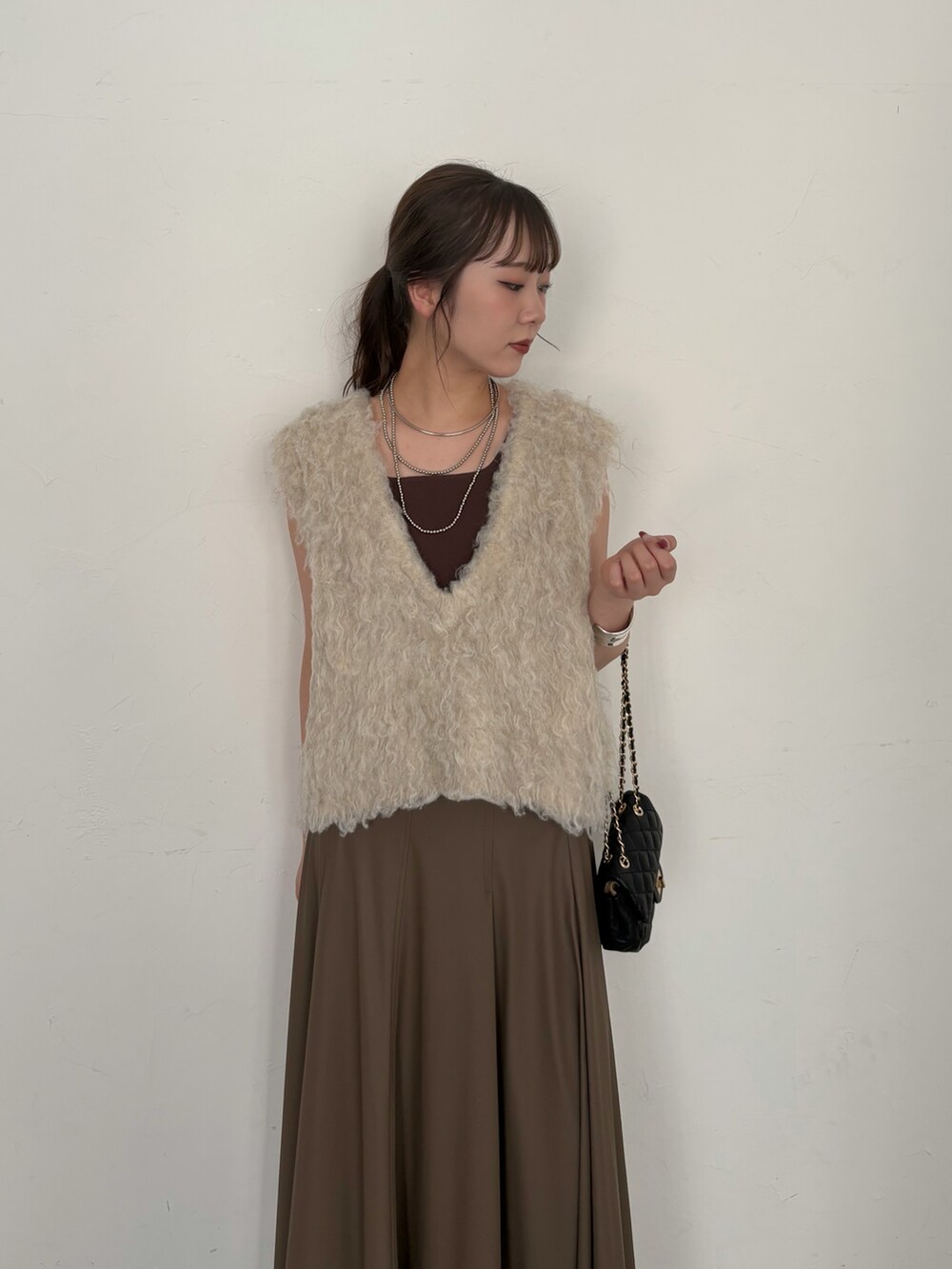 ブラウン系のタンクトップ、ブラック系のショルダーバッグ、ベージュ系のニット/セーターを着用したレディースの夏コーディネートの7枚目の写真