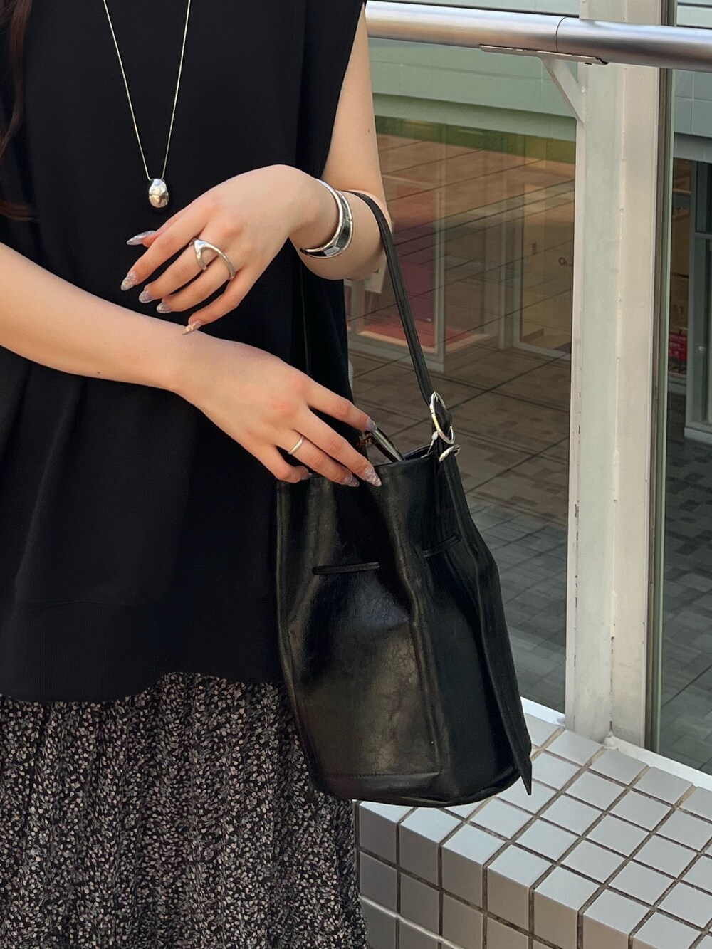 ブラック系のスウェット、ピンク系のスカート、ブラック系のバッグを着用したレディースの夏コーディネートの8枚目の写真