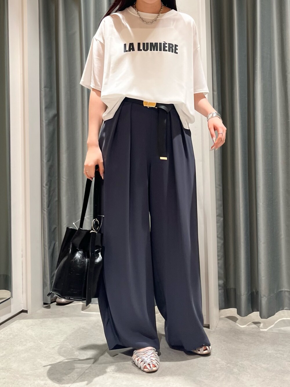 グレー系のスラックス、ブラック系のバッグ、シルバー系のパンプスを着用したレディースの夏コーディネートの3枚目の写真