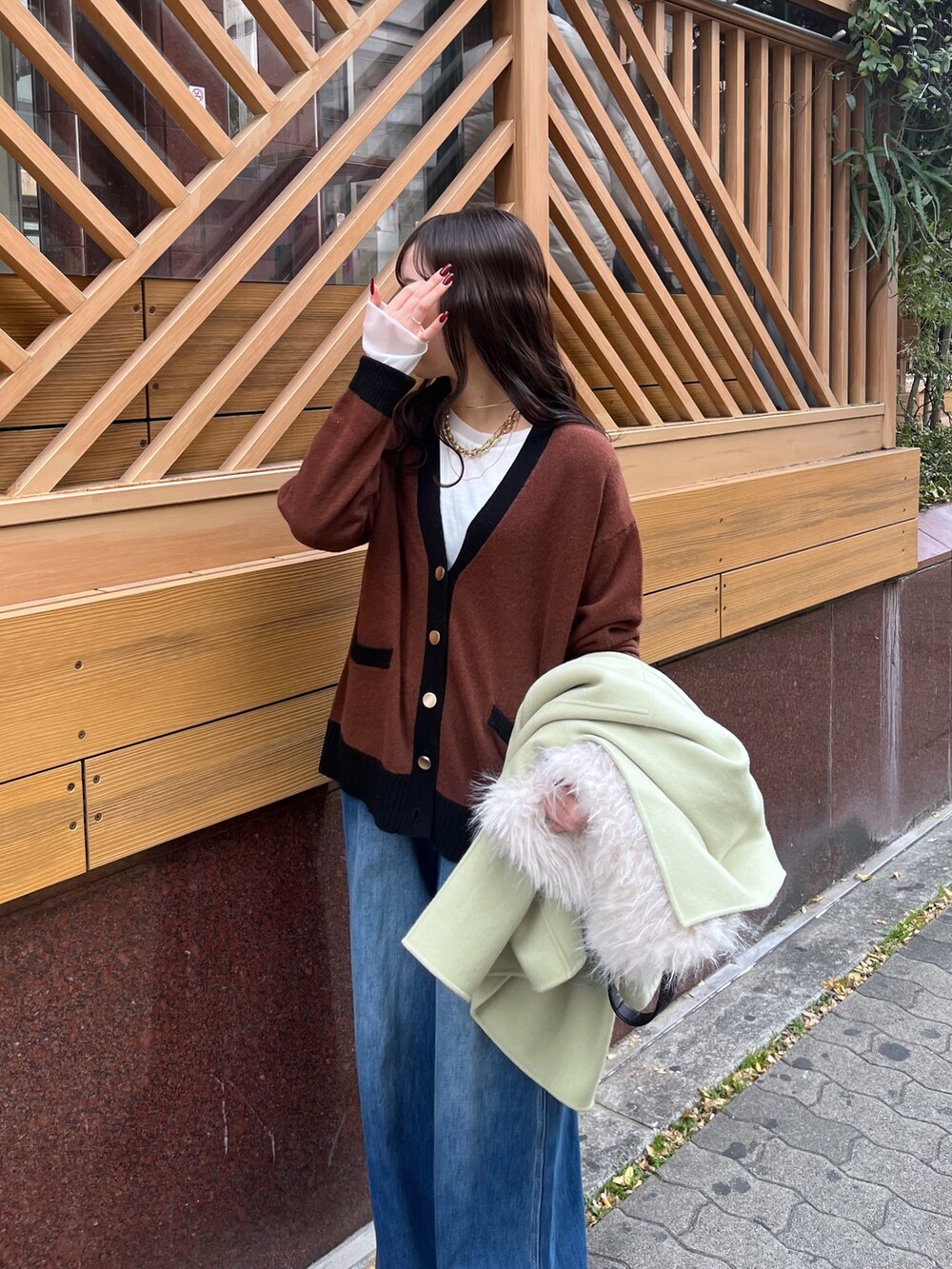 ブルー系のデニムパンツ、グリーン系のその他アウター、ホワイト系のショルダーバッグを着用したレディースの冬コーディネートの3枚目の写真