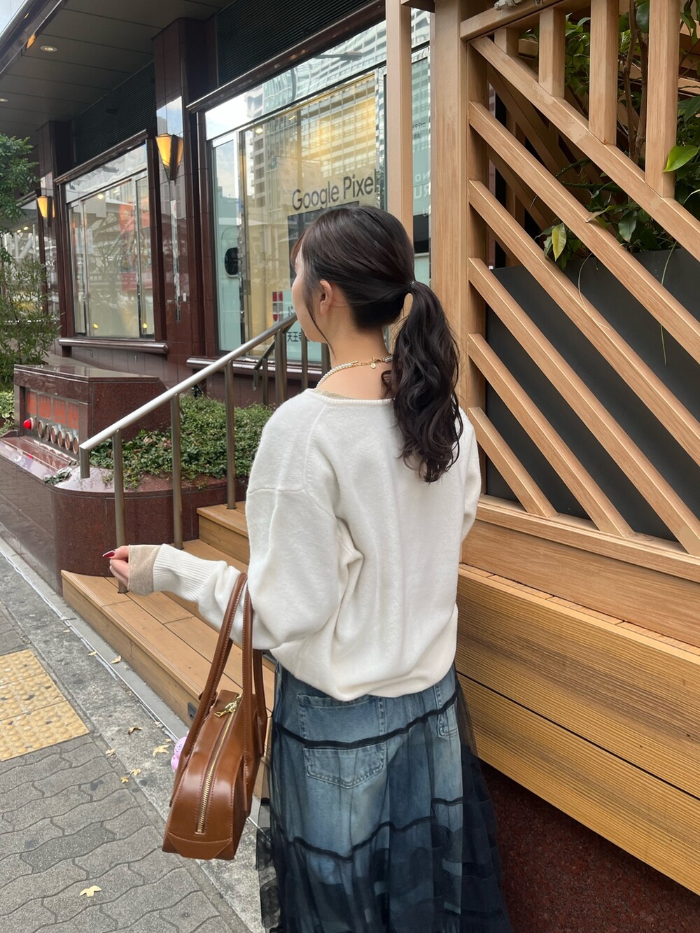 ブルー系のデニムパンツ、ブラック系のスカート、ホワイト系のニット/セーターを着用したレディースの冬コーディネートの7枚目の写真