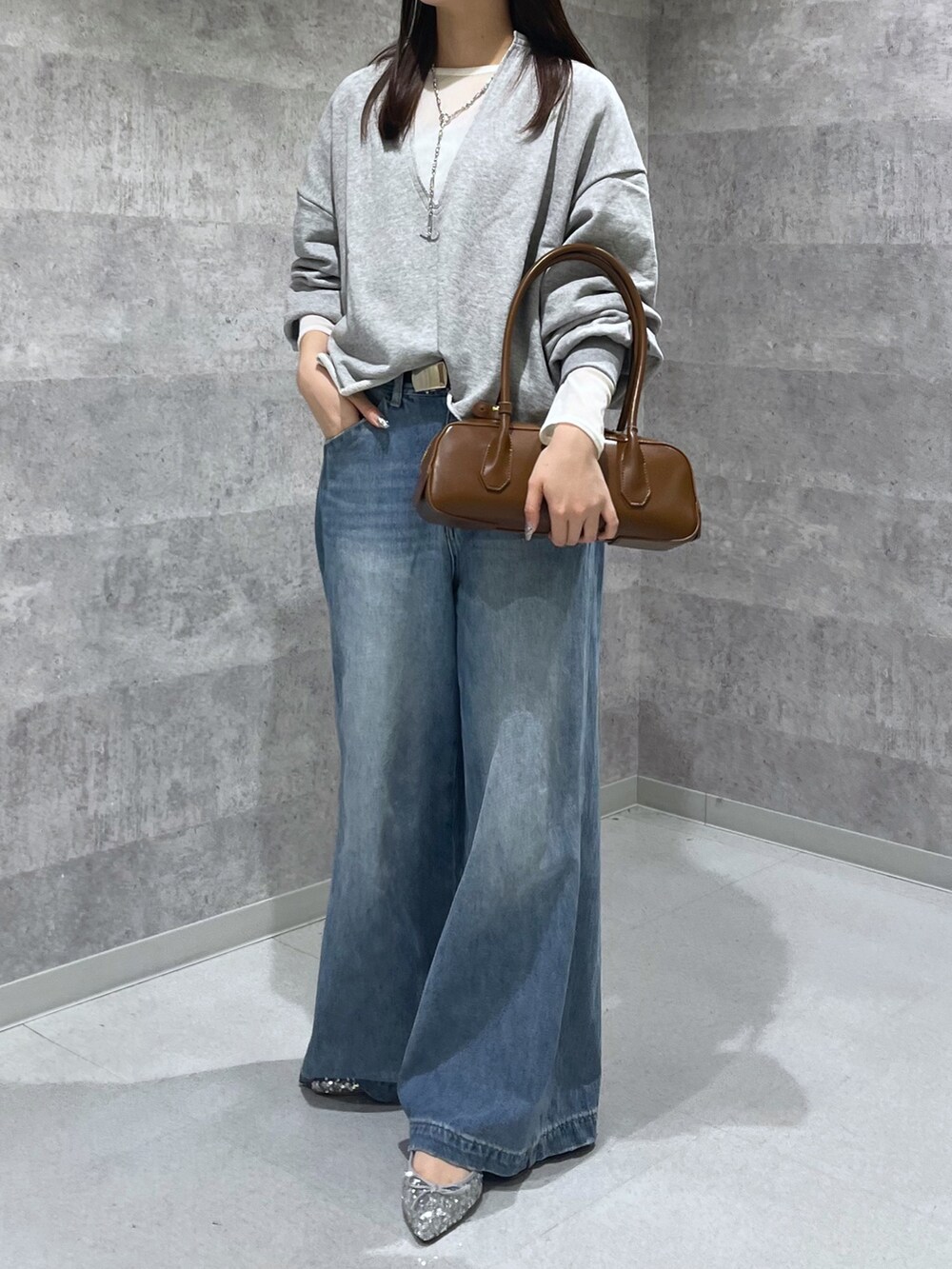 ブルー系のデニムパンツ、シルバー系のパンプス、グレー系のTシャツ/カットソーを着用したレディースの秋コーディネートの2枚目の写真